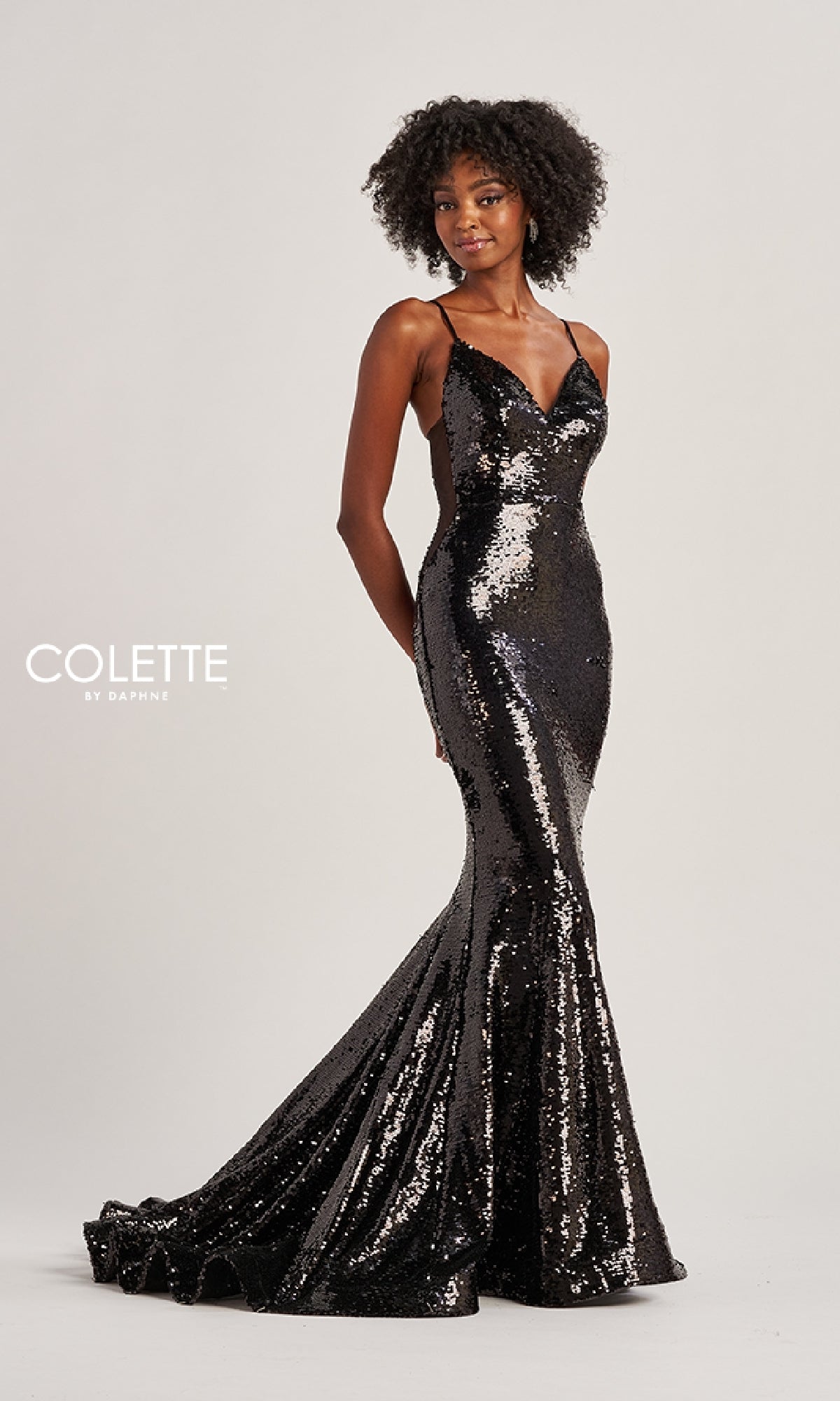 A woman models the Colette CL8615, a fitted, floor-length black sequin mermaid gown with thin straps, standing against a plain background.